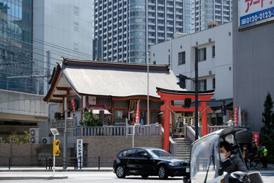 Man riding vehicle against hibiya shrine on street in city