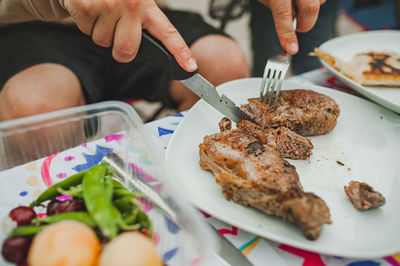 Hand cuts delicious piece of meat steak on white plate with fork and knife. selective focus