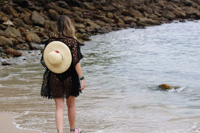 Rear view of woman standing at beach