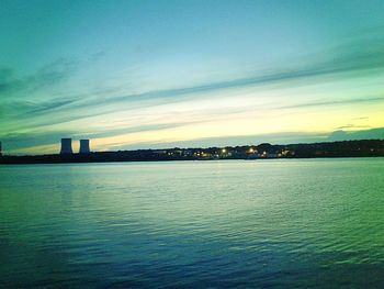 View of city at waterfront against cloudy sky
