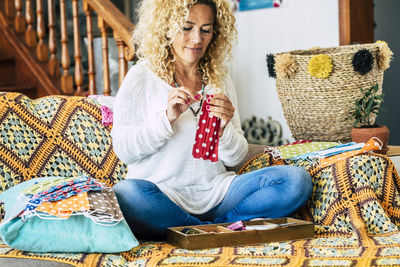 Woman stitching mask while sitting at home