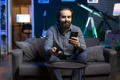 Young man using mobile phone while sitting on sofa at home