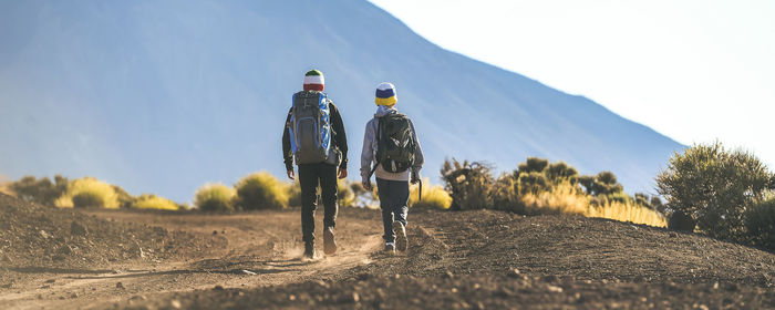 Rear view of men walking on mountain against sky