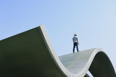 Rear view of man standing against clear blue sky