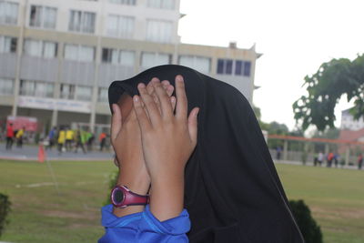 Close-up of woman covering face while standing in campus