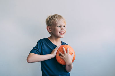 Portrait of smiling boy holding ice cream against white background