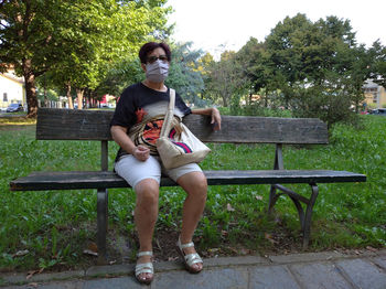 Full length of woman sitting on bench in park