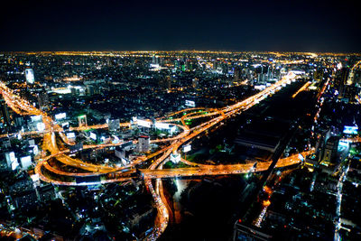 High angle view of illuminated street amidst buildings in city at night