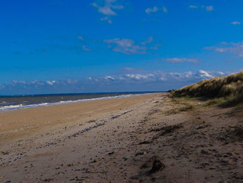 Scenic view of beach against cloudy sky