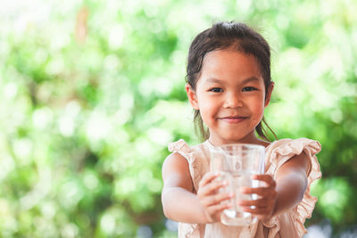 Close-up of girl holding water glass outdoors