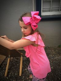 Cute girl looking away while standing against pink wall