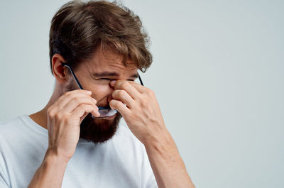 Portrait of young man drinking water against white background